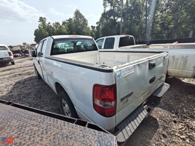 Ford F-150 extended cab pickup truck in a salvage lot showing rear and cargo bed with tailgate and taillight assembly.