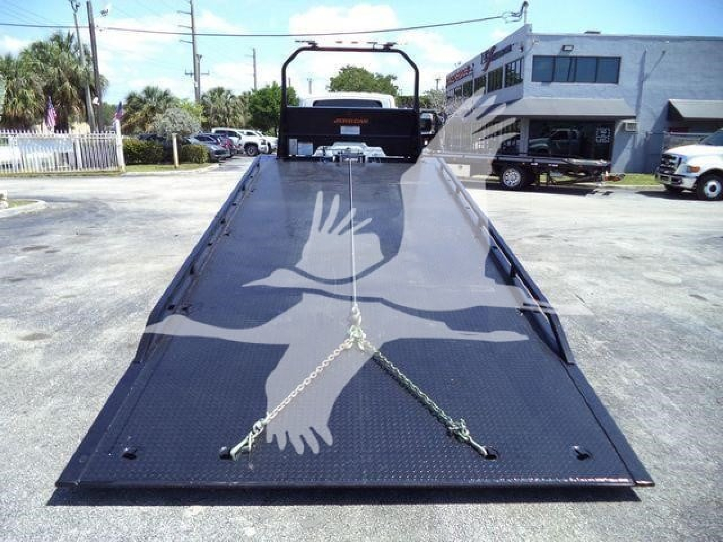 Flatbed tow truck bed with safety chains and dove graphic, viewed from rear, International MV stock image.