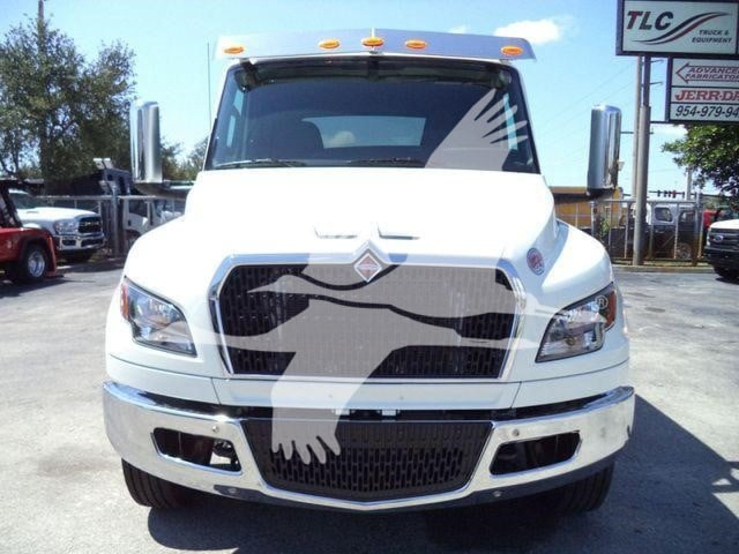 International MV rollback truck front view showing large grille, chrome bumper, and mirrors.