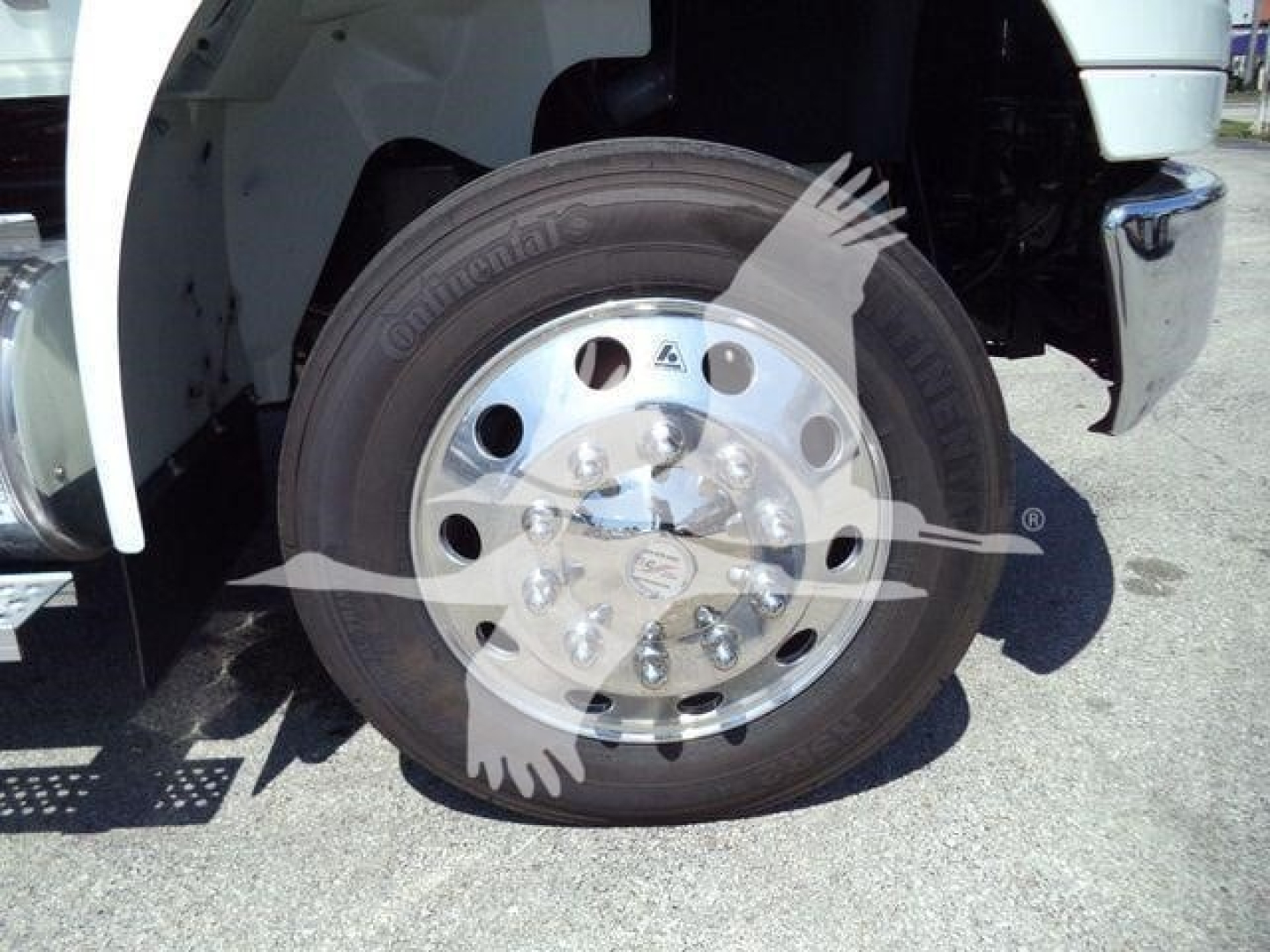 Front wheel showing large steel rim with multiple lug nuts and tire on a rollback truck.