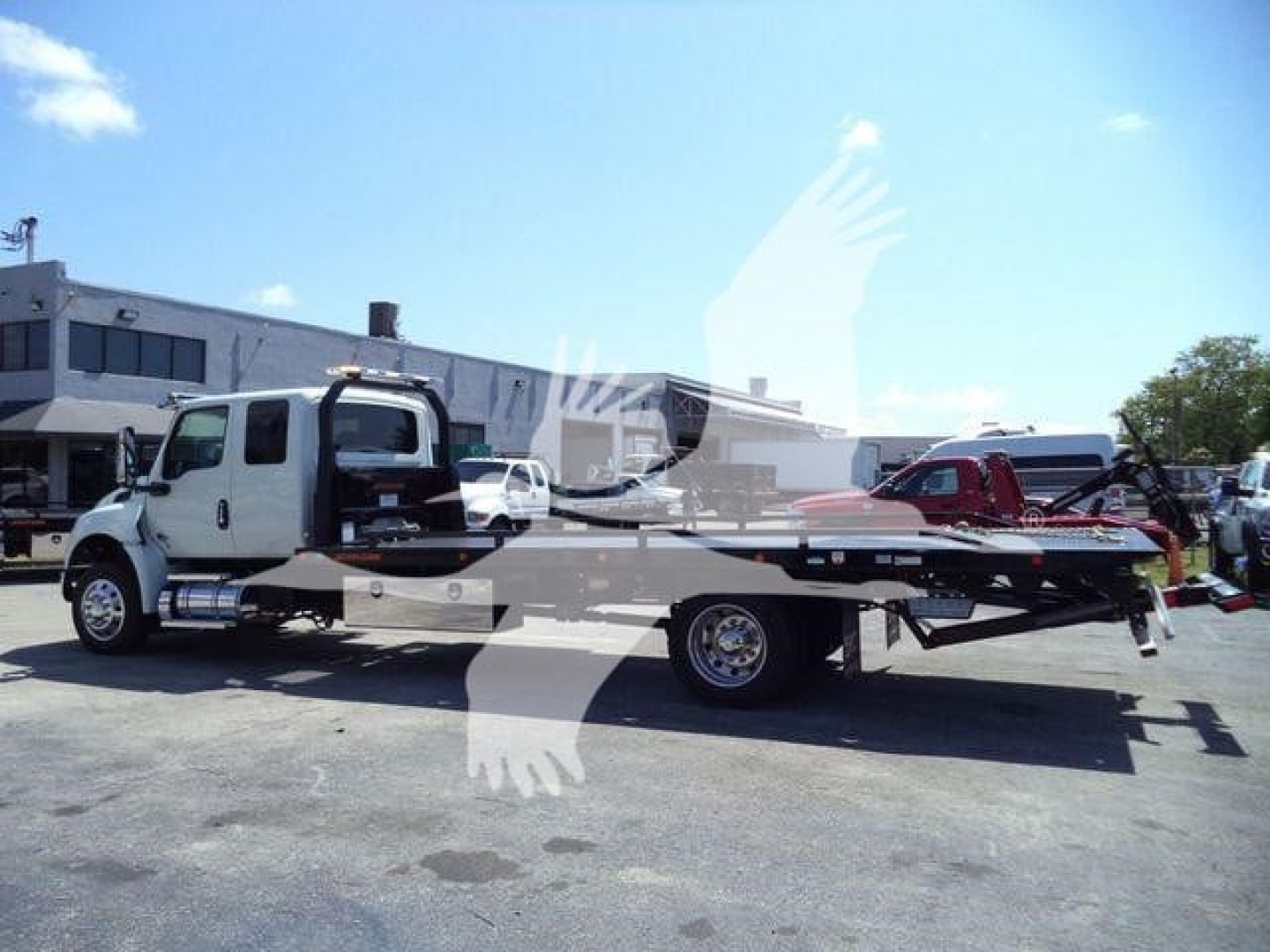 Truck bed tow truck on a flatbed rollback with cab and long carrier in a dealership lot