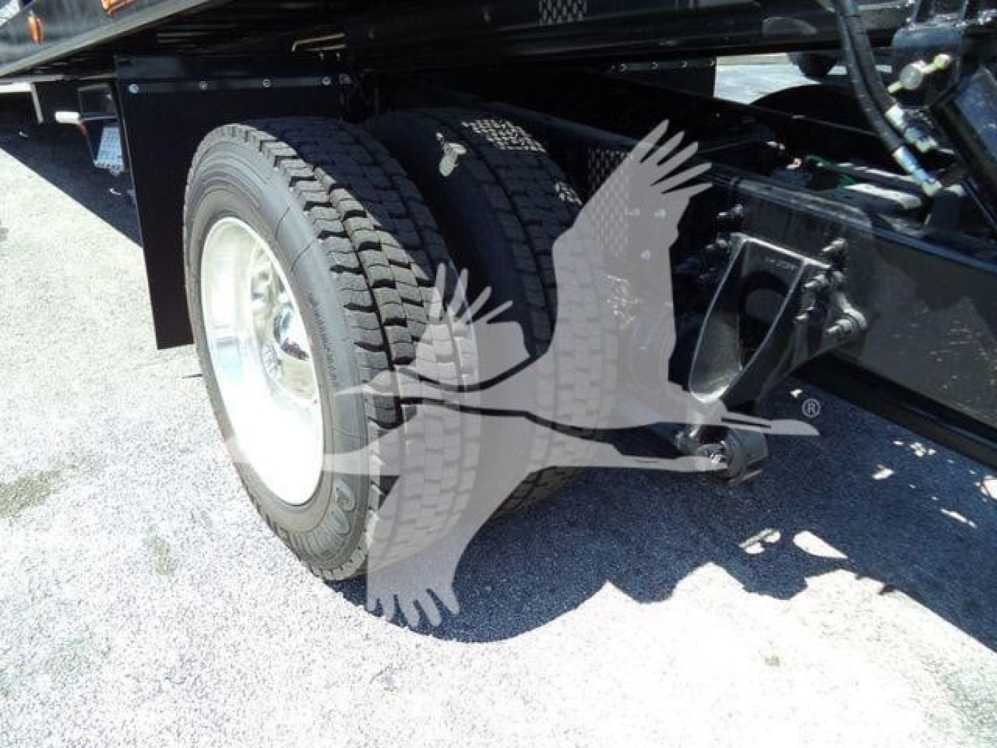 Truck rear wheel and suspension components with part of frame visible; no legible text readable