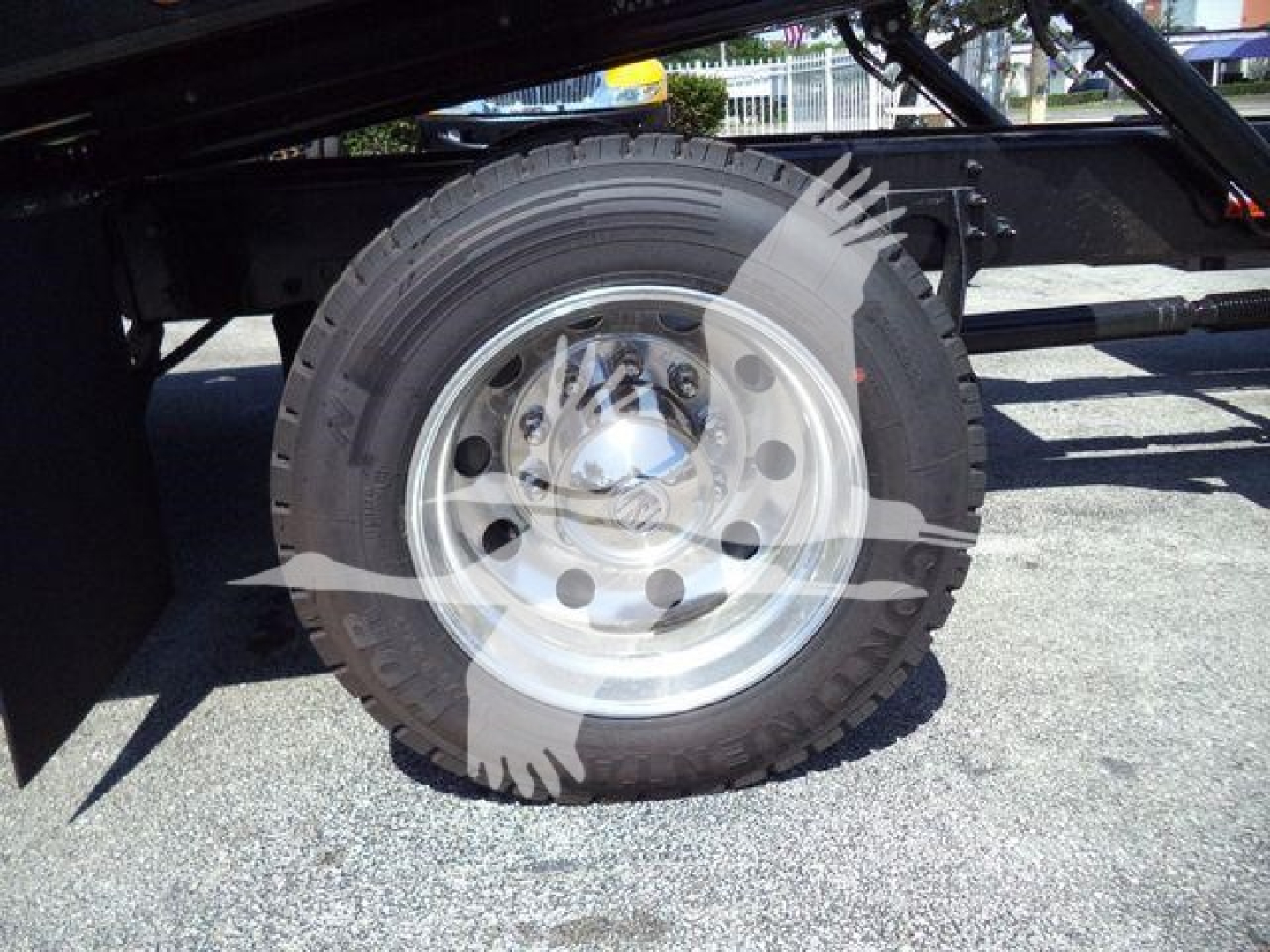 Wheel and tire of a heavy-duty truck trailer showing steel rim and treaded tire undercarriage componentry visible.