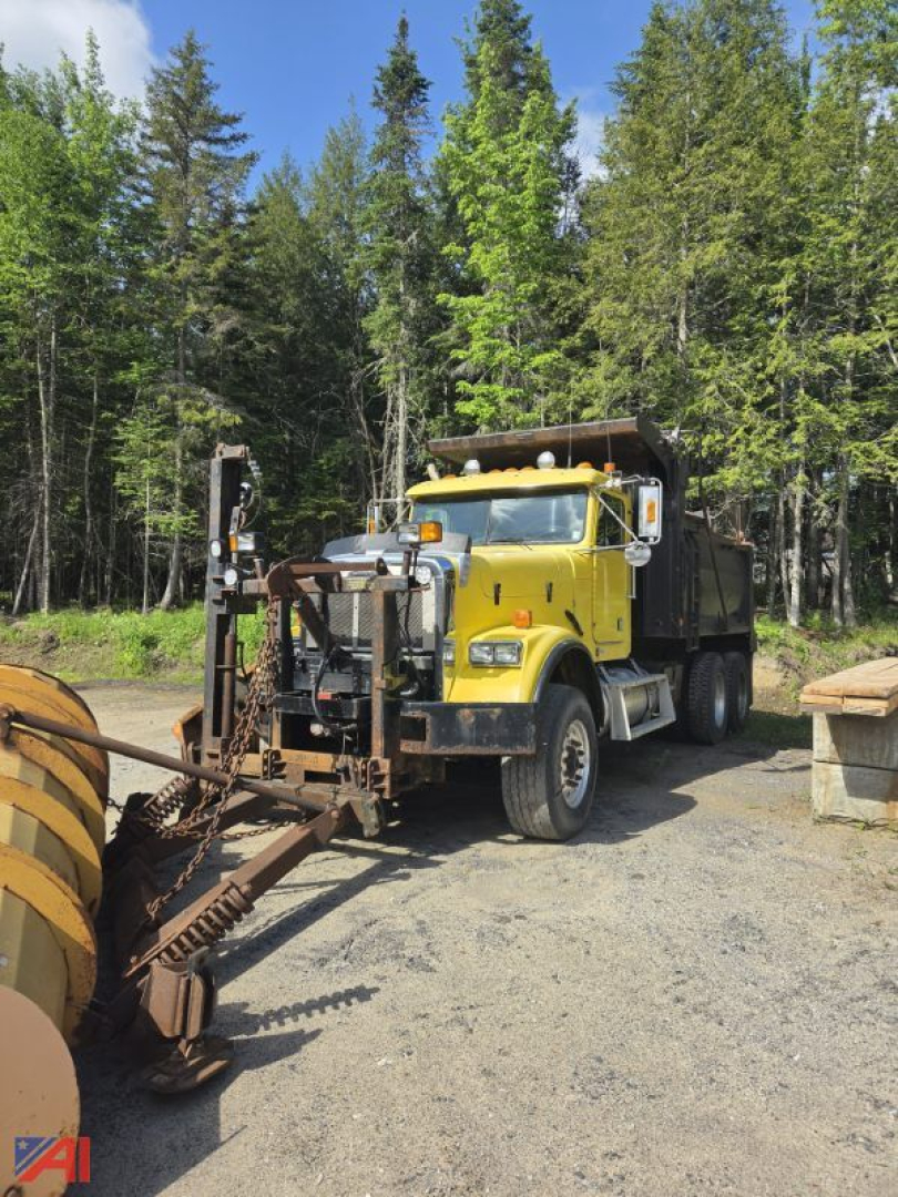Yellow Freightliner FLD120 SD dump truck with plow attachment in a wooded lot.