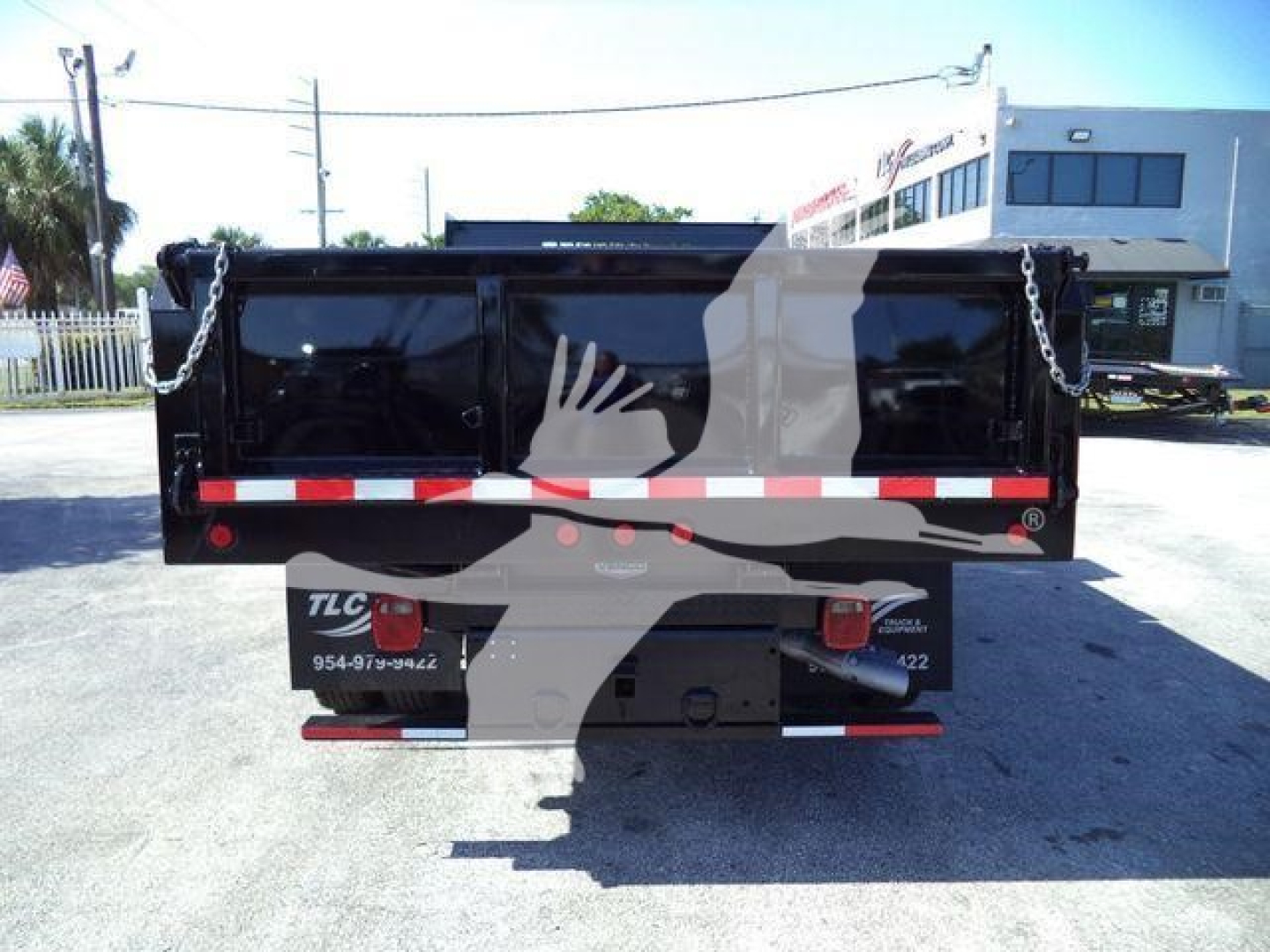 Dump truck bed of a 2019 Ford F550 in-service rear view with black dump box and chain links on both corners.