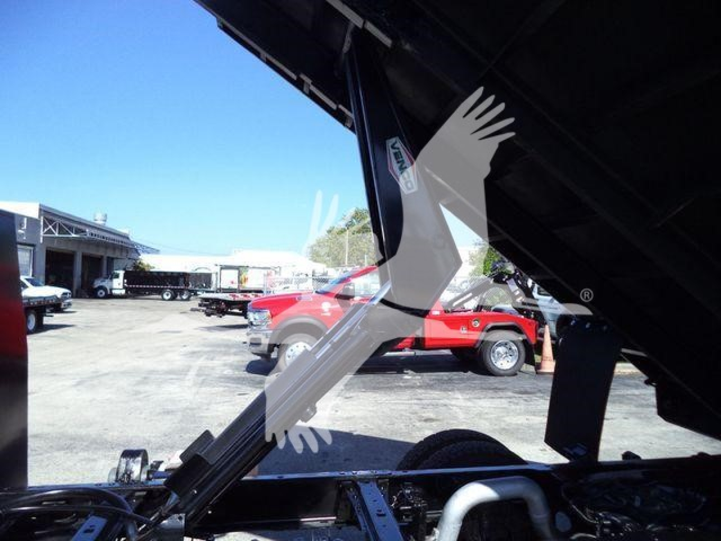 Truck bed dump body showing hydraulic lift and undercarriage of a 2019 Ford F550 in a used truck lot.