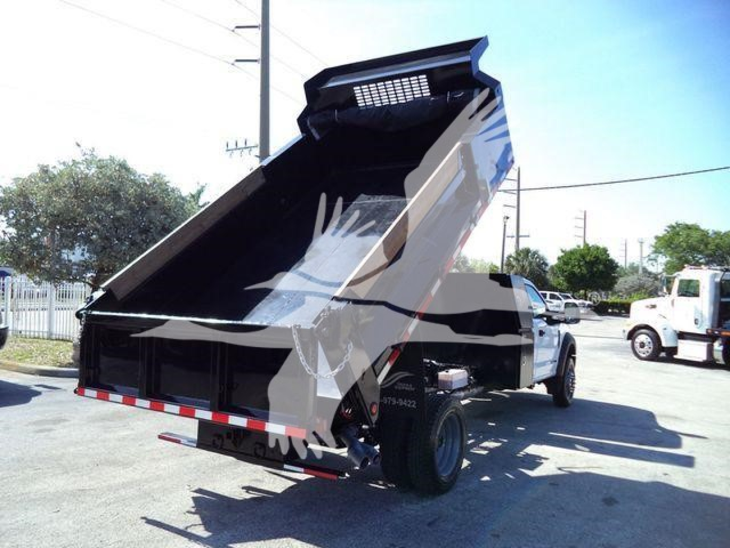 Dump truck bed raised on a 2019 Ford F550 in-service showing hydraulic mechanisms and rear cargo area.
