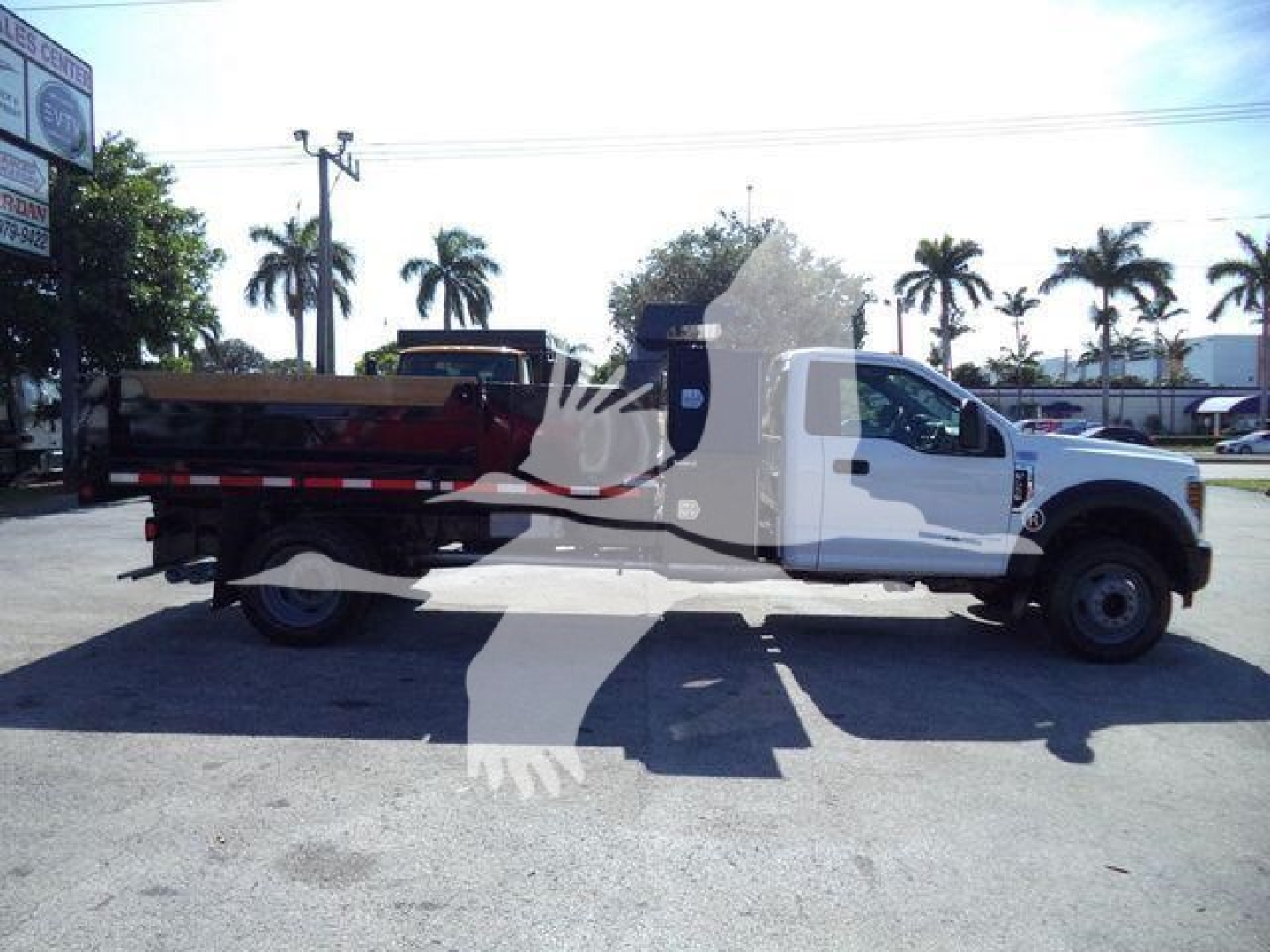 2019 Ford F550 dump truck side view showing white cab and red dump bed. Stock number T00690FM and category details visible in listing background.