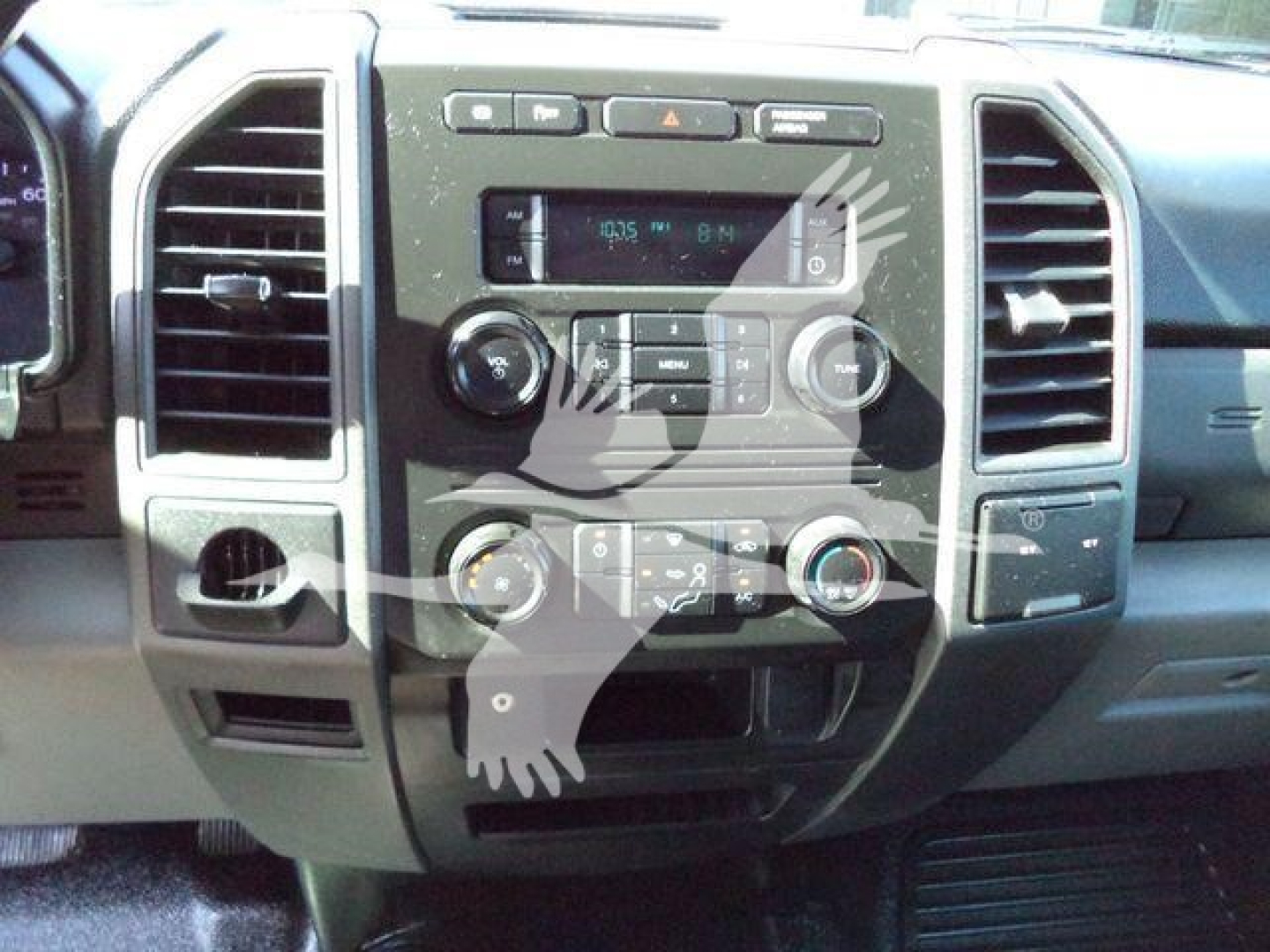 Ford F-550 dash panel showing center console with radio, climate controls, and multiple knobs; air vents on either side; dashboard in a pickup truck interior.