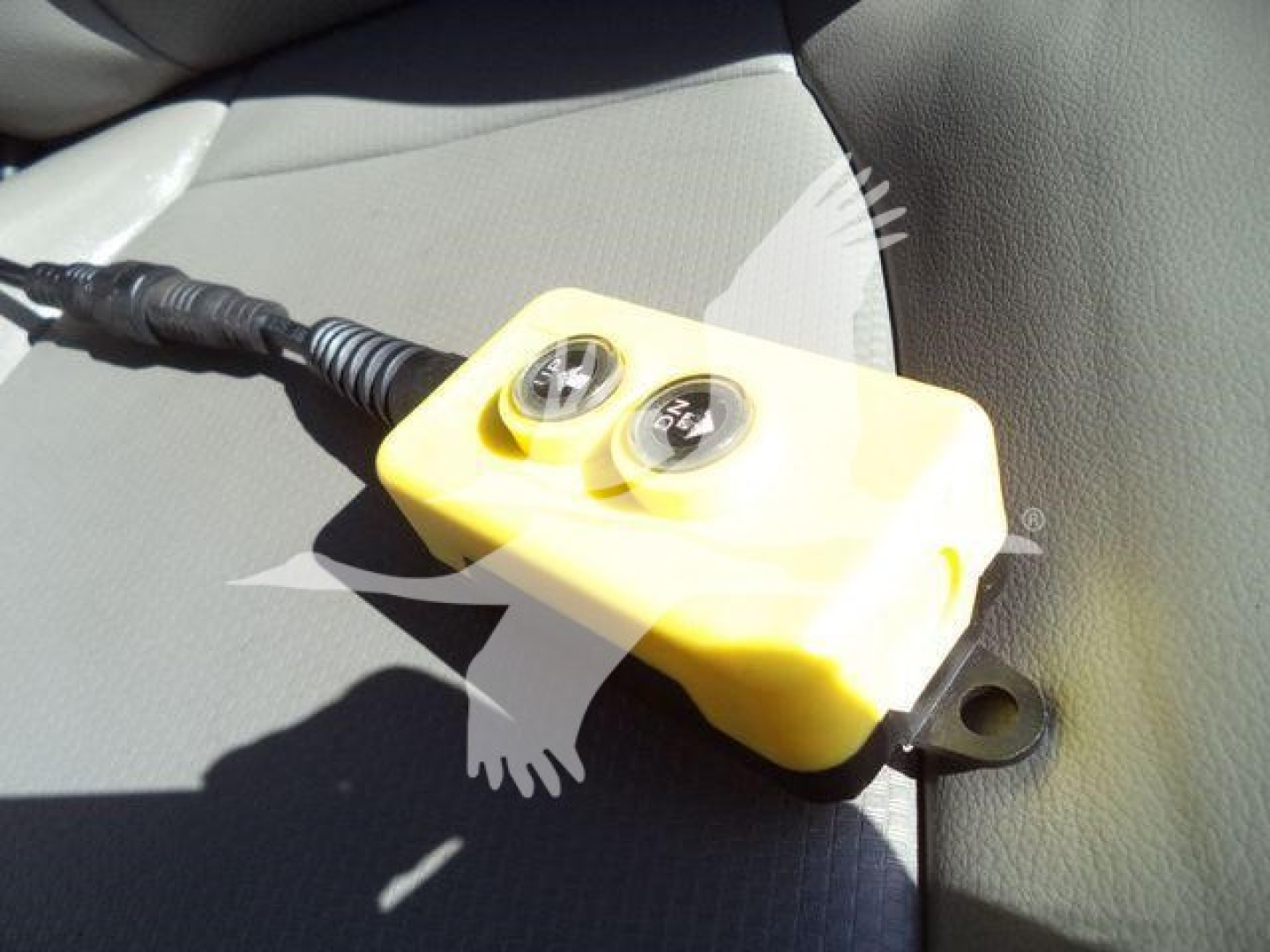 Yellow two-gauge device on a truck seat with a cable attached, likely a diagnostic or control unit.