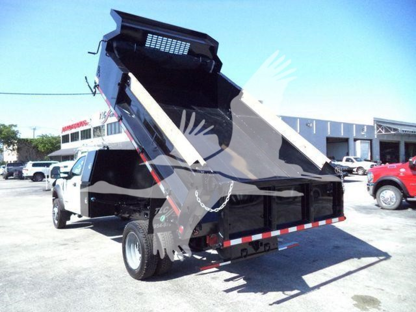 Dump bed truck with hydraulic dump raised, visible text includes 'T00690FM' and 'NewUsed: Used' from listing context. Image shows a white Ford F-550 dump truck in a dealership lot.