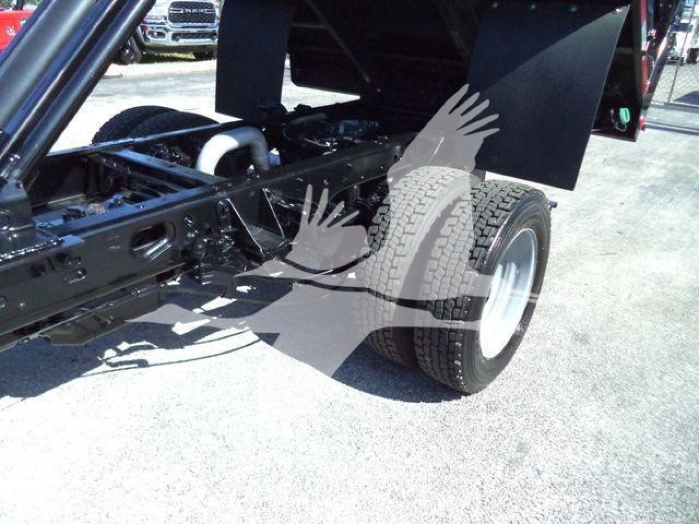 Ford F550 dump truck chassis showing rear wheel and suspension with exposed frame and hydraulic dump mechanism.
