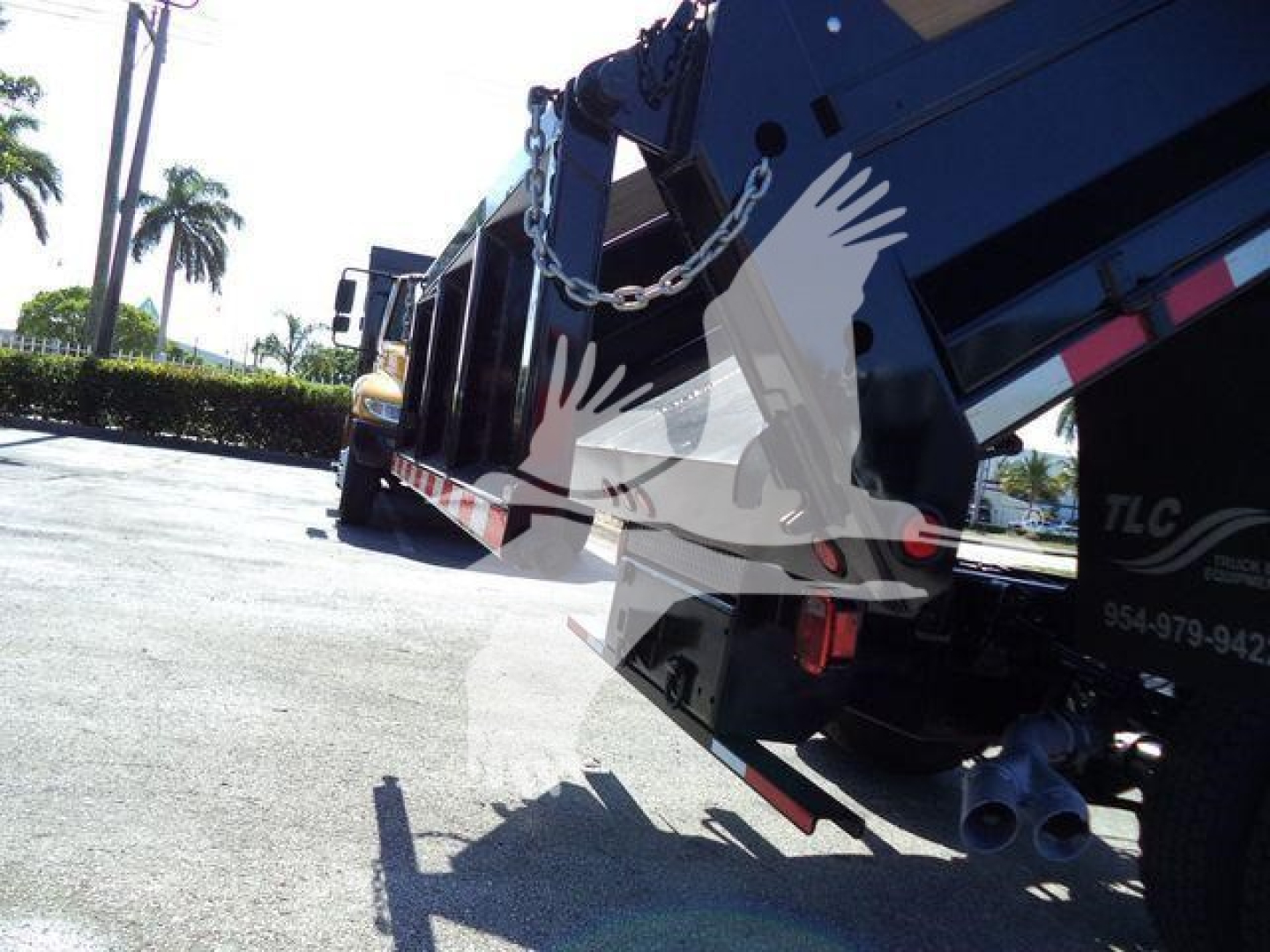 Ford F550 dump truck in-service rear view showing hoist mechanism and dual exhaust tips.