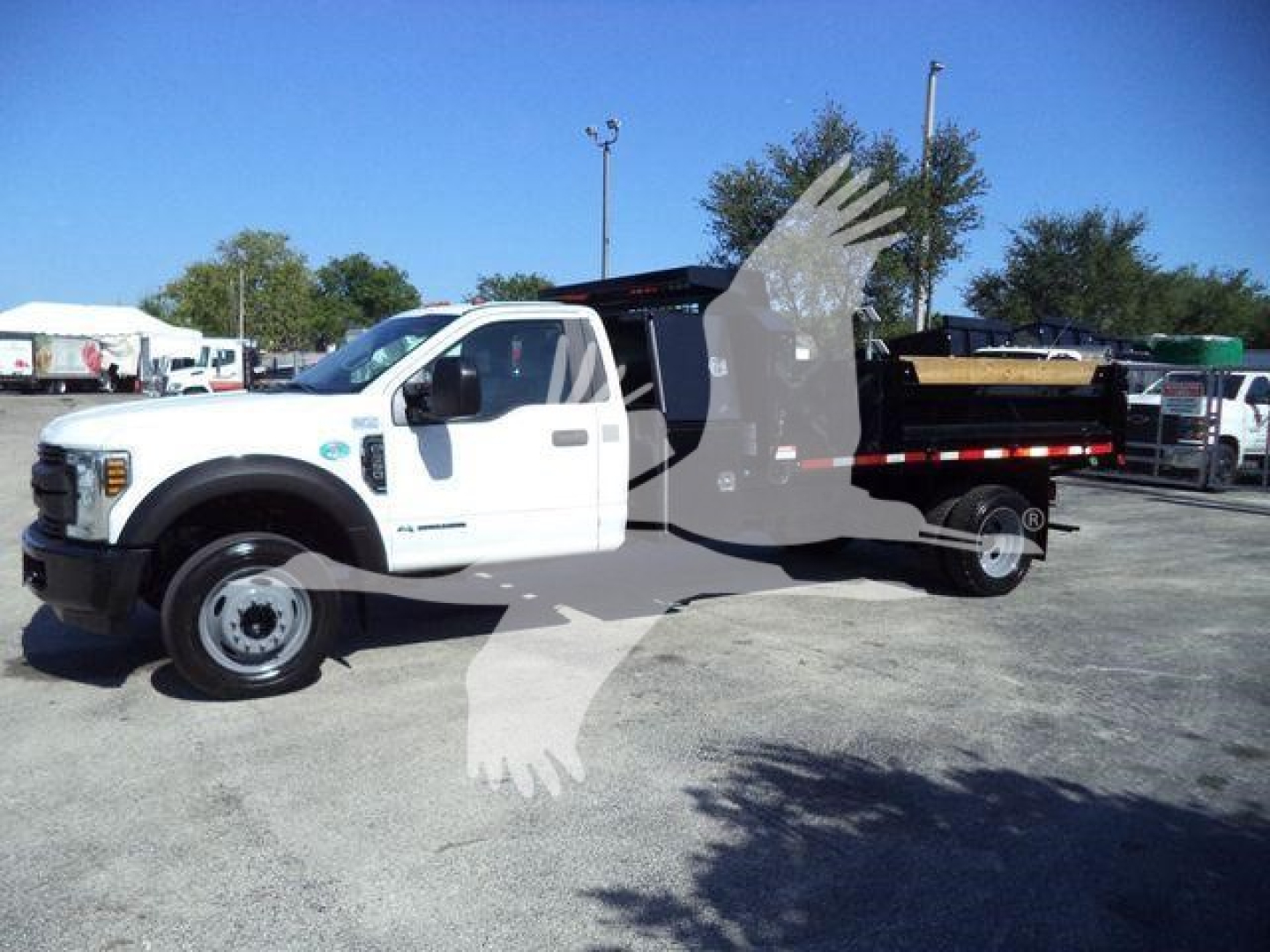 Ford F-550 dump truck side view showing white cab and black dump bed with wooden material.