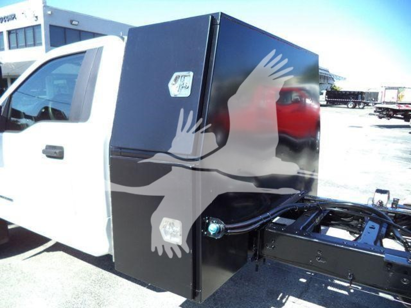 Ford F-550 dump truck cab with a large black utility box mounted behind the cab, side view showing box doors with silver handles.