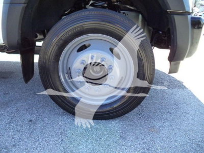 Dump truck wheel and tire with alloy hubcap visible on the front wheel of a 2019 Ford F-550 dump truck viewed from the side.