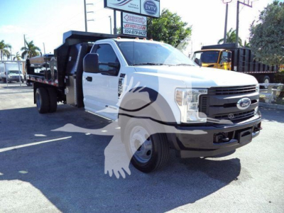 Ford F-550 dump truck in-service with white cab and black grille, side view showing dump bed and equipment.