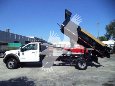 Ford F-550 dump truck with bed raised, side view showing white cab and black dump body.