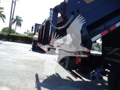 Ford F550 dump truck in-service rear view showing hoist mechanism and dual exhaust tips.
