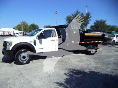 Ford F-550 dump truck side view showing white cab and black dump bed with wooden material.