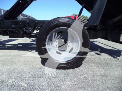 Truck wheel and undercarriage view showing a single rear tire and chassis on a Ford F550 dump truck with hydraulic components nearby.