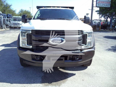 Front view of a Ford F-550 dump truck with large grille, white cab, and black bumper. Emblem centered on grille and side mirrors visible.