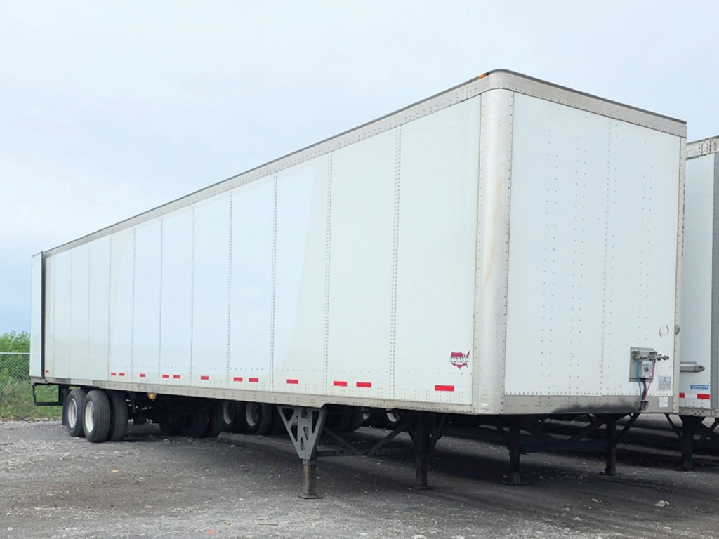 Semi-trailer van showing aluminum exterior with wheel axles and rear hitch; side panels with riveted seams; no visible branding.