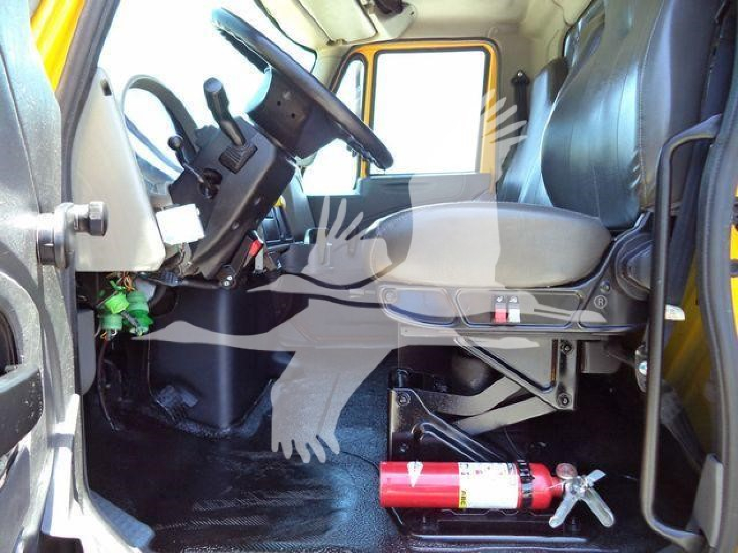 Cab interior of 2019 International Durastar 4300 with steering wheel, driver seat, dashboard, and red fire extinguisher on the floor.