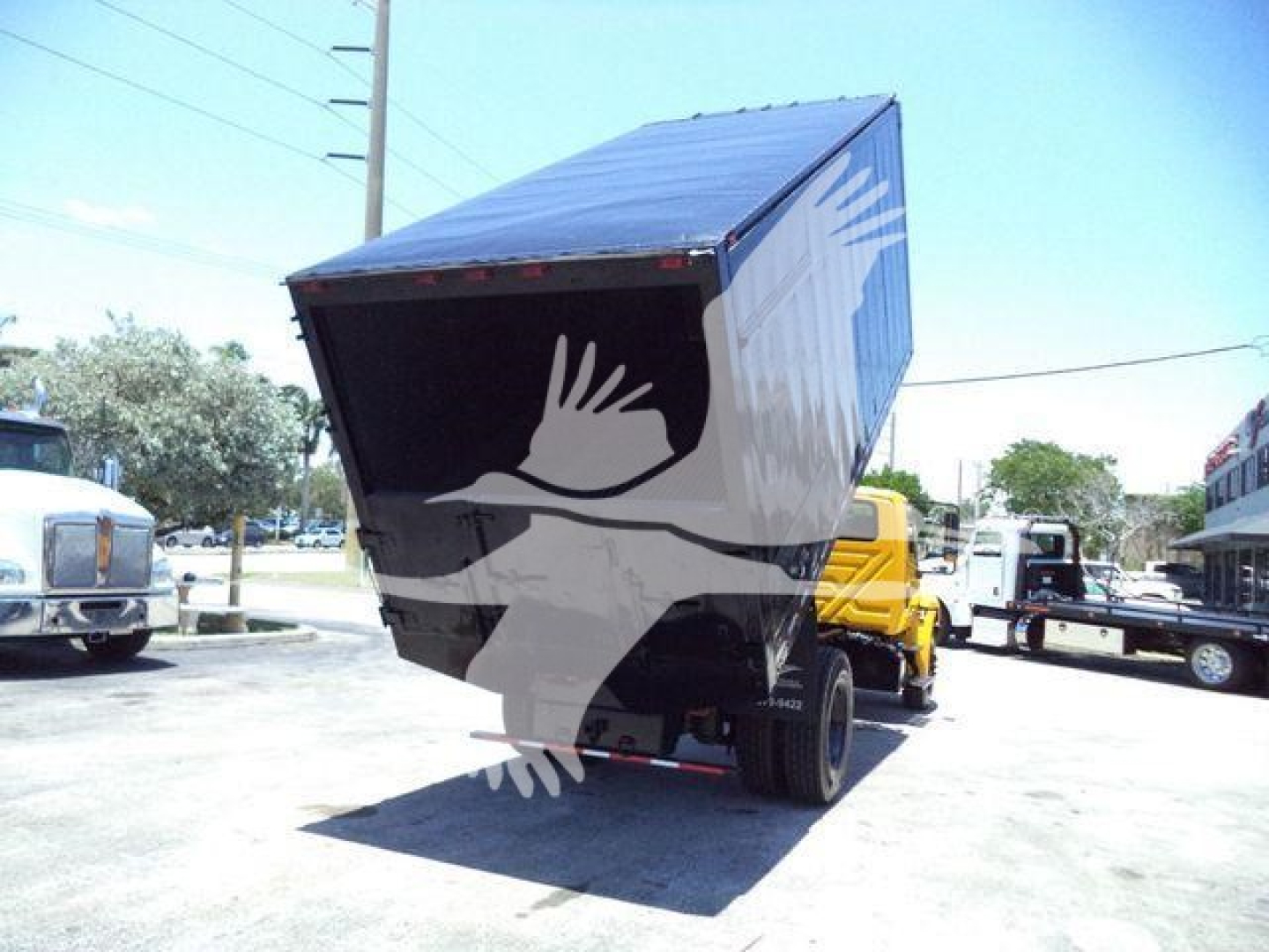 Truck dump body tilted up showing cargo box and rear wheels in a lot.