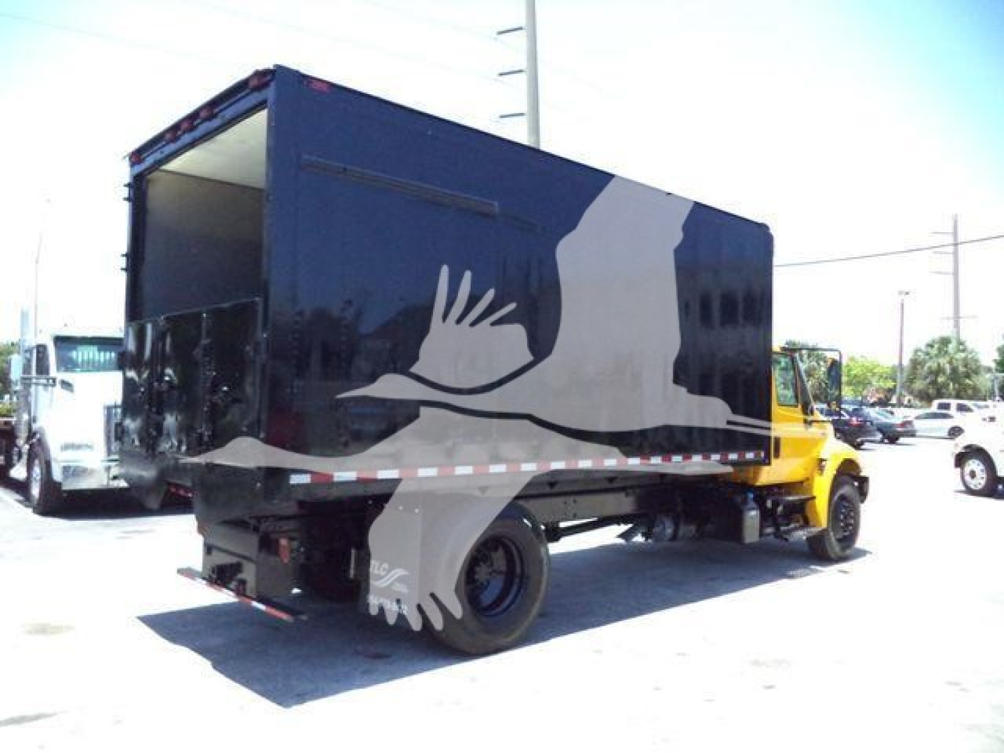 Truck with a dark blue dump body showing a large white silhouette graphic; cargo area open at rear; International Durastar 4300 chassis in yellow.