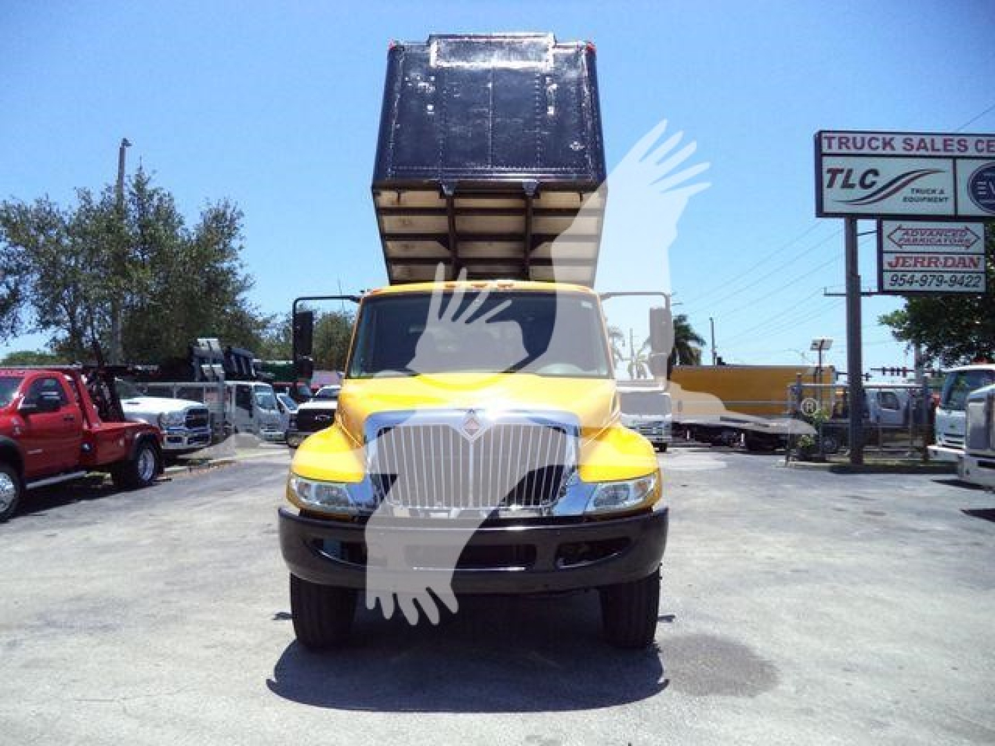 Truck front view of a yellow and brown 2019 International Durastar 4300 with raised dump bed in a dealership lot.