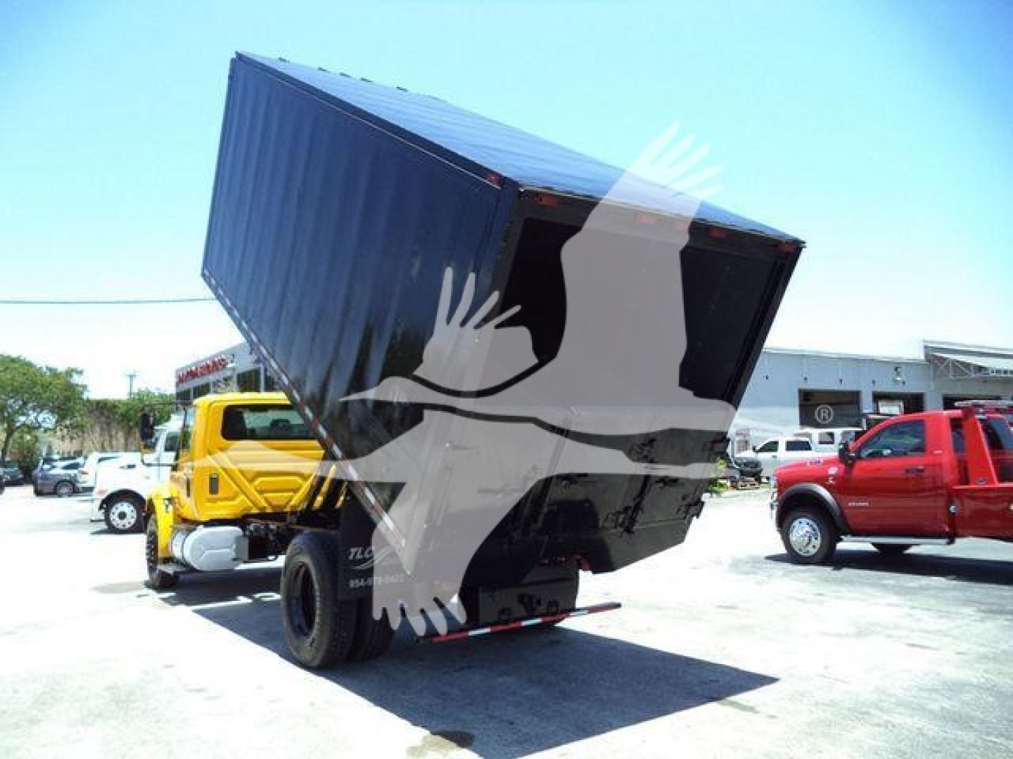 Truck bed raised showing container on International 4300 chassis and surrounding lot