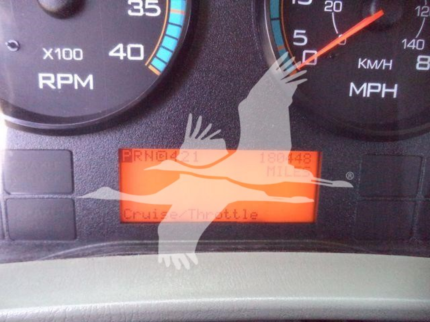 Dashboard display showing orange digital readout with text including PRND (partially), Cruise Control, and Yukon-like graphic overlay. Instrument cluster with RPM gauge and MPH gauge visible.