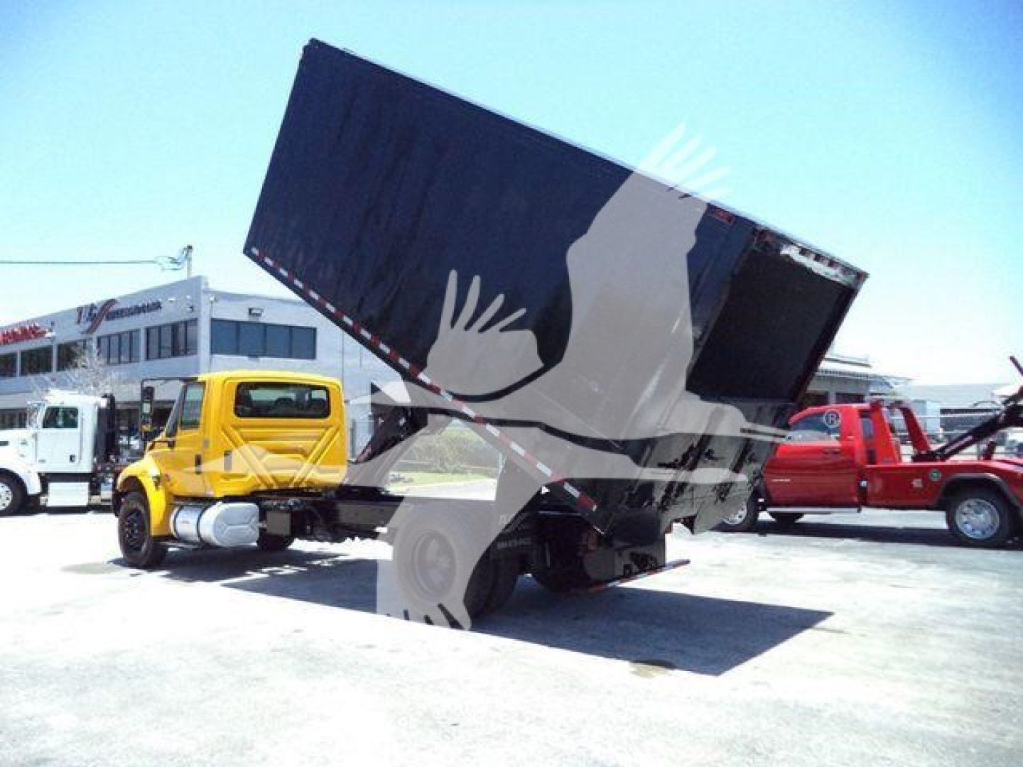 Truck with dumping bed raised in a yard, International Durastar 4300 dump truck in foreground