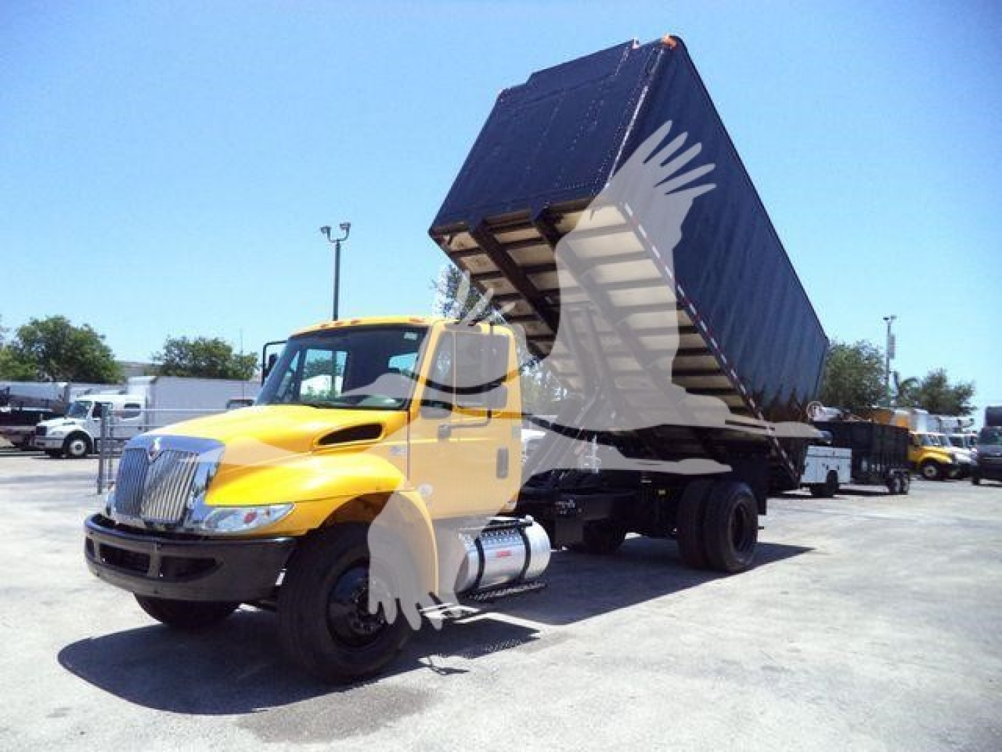 International Durastar 4300 dump truck with yellow cab and hydraulic bed raised in a lot.