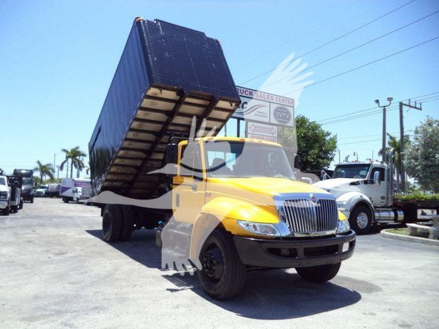 2019 International Durastar 4300 dump truck in service position with bed raised, yellow cab, black dump body, front grille and headlights visible.