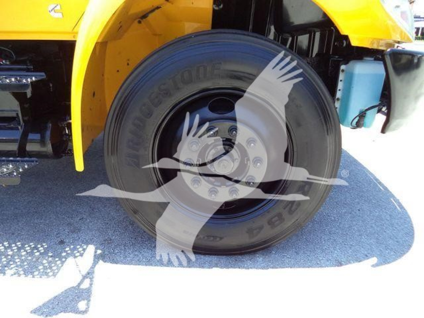 Front wheel and fender of a yellow International Durastar 4300 truck showing a large black tire with visible Bridgestone branding and wheel hub details.