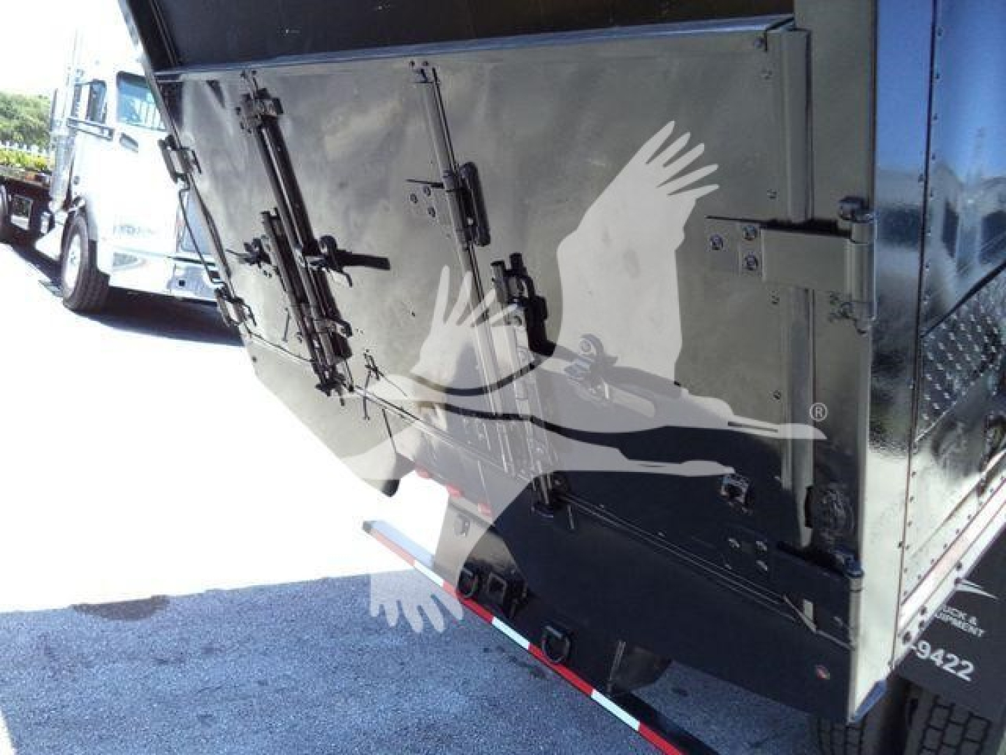Rear view of a 2019 International Durastar 4300 chipper truck showing rear tailgate with latches and hydraulic mechanism.