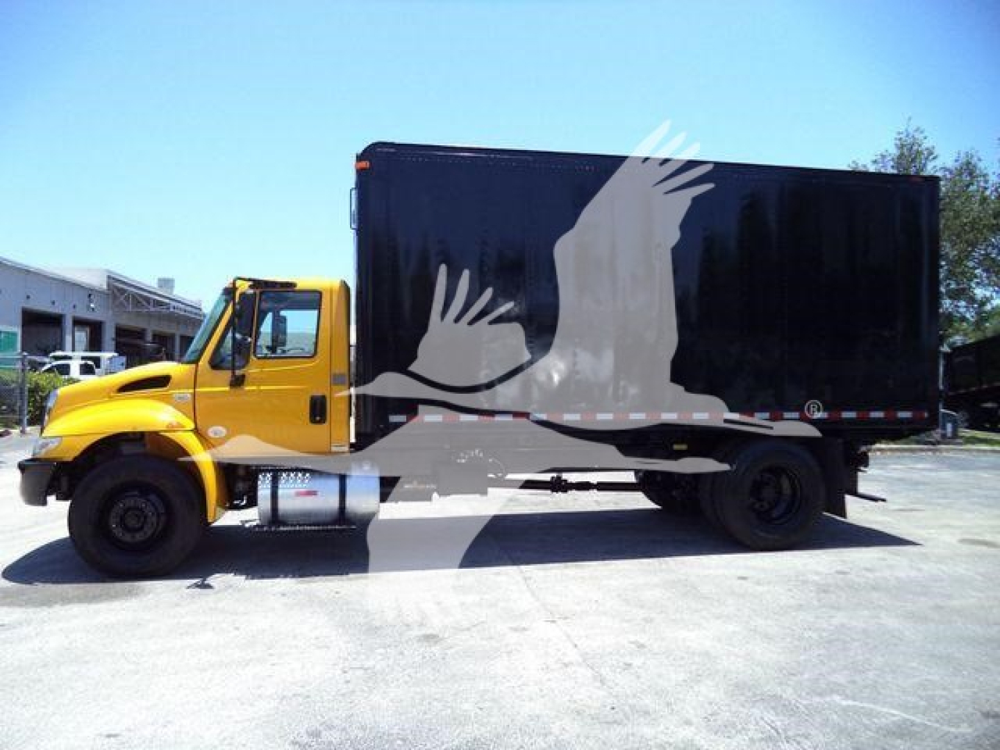 Truck side view showing a yellow International Durastar 4300 cab with a large black box body.