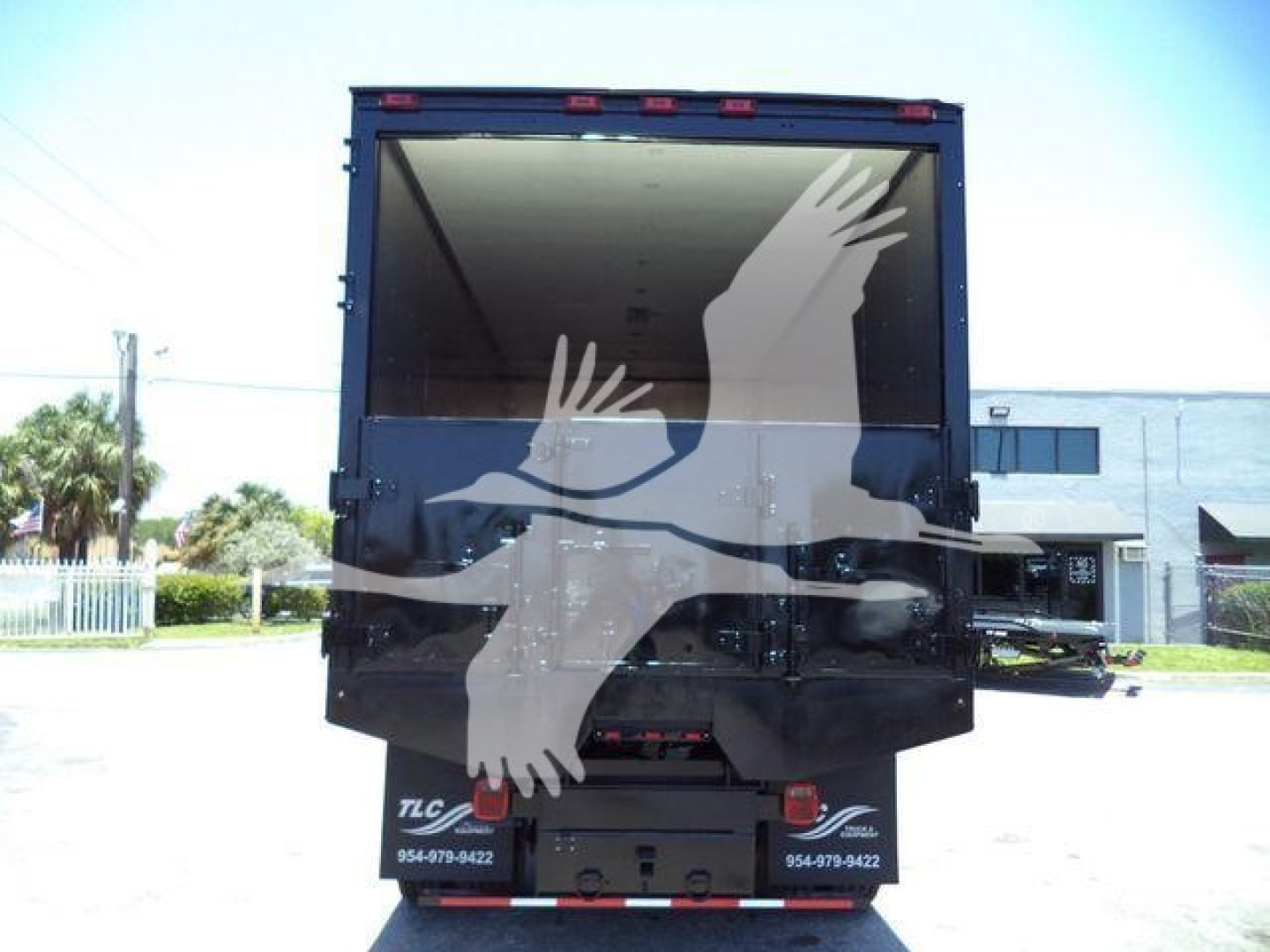 Truck bed of a 2019 International Durastar 4300 dump/chipper body showing rear open box and logo silhouettes overlay