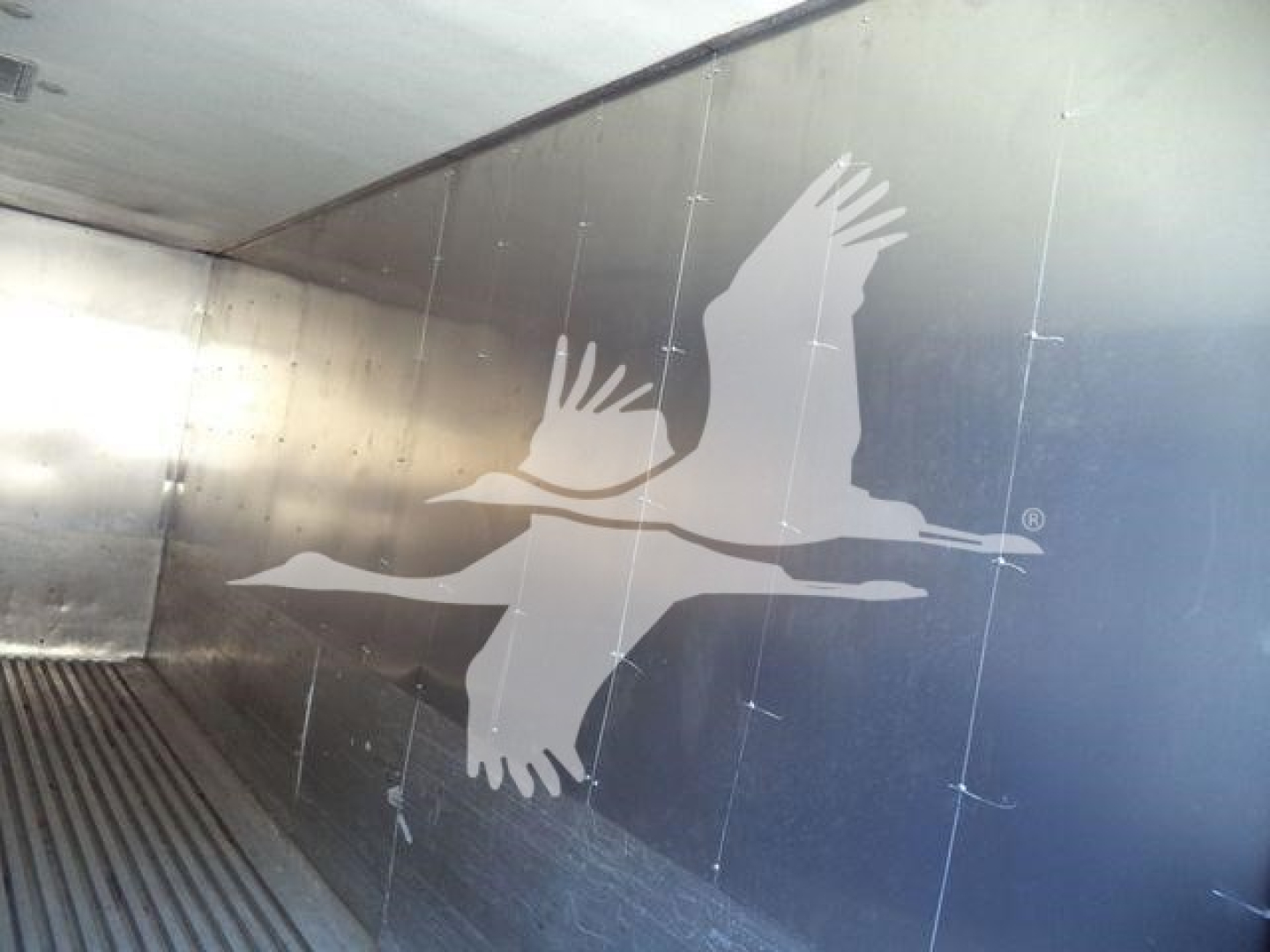 Truck bed interior showing a white logo of flying birds painted on metal wall
