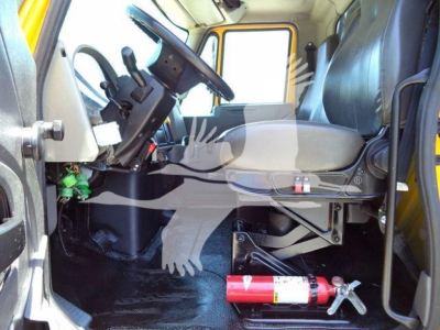 Cab interior of 2019 International Durastar 4300 with steering wheel, driver seat, dashboard, and red fire extinguisher on the floor.