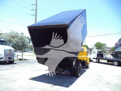 Truck dump body tilted up showing cargo box and rear wheels in a lot.