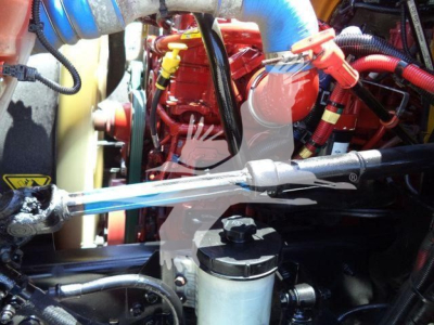 Engine bay of a 2019 International Durastar 4300 showing red engine block, blue hoses, yellow cap, and various cables and components.
