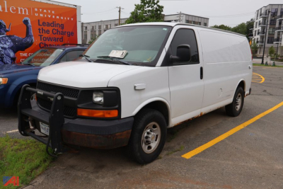 2005 Chevrolet Express cargo van in a parking lot with front bumper guard and side entry, white color, visible headlights and black front grille.