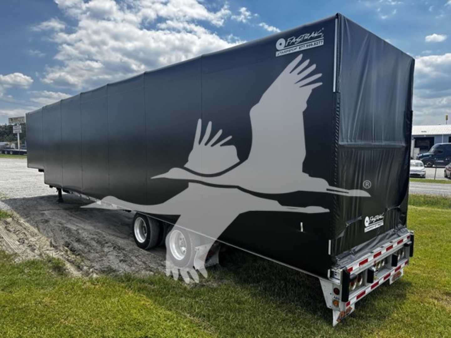 Trailer side view showing a curtain side with a large white bird graphic and a dark tarp; rear with lights and bumper visible, 2017 Reitnouer Bubba Drop
