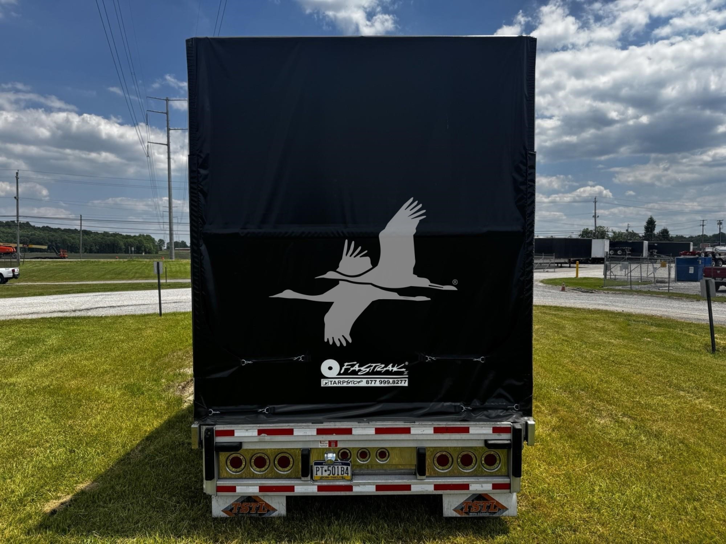 Back of a 2017 Reitnouer Bubba Drop curtainside trailer with a black tarp and a white bird logo, bumper lights, and license plate visible.