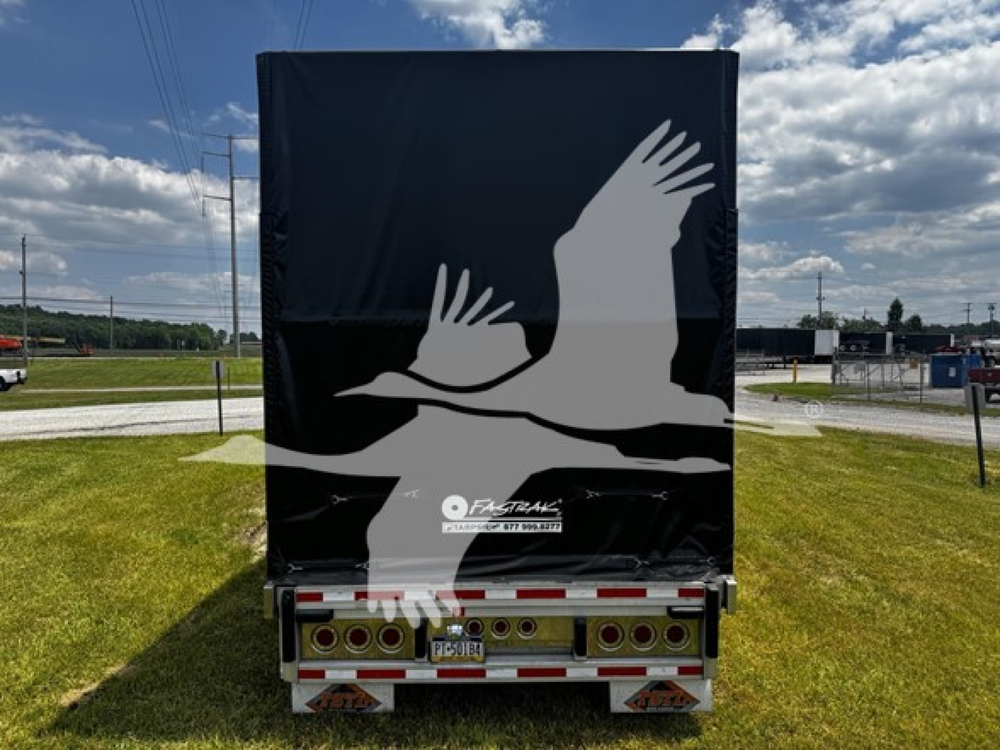 Trailer rear view of a 2017 Reitnouer Bubba Drop curtainside trailer with a black tarpaulin cover featuring a white bird silhouette, lights and license plate visible.
