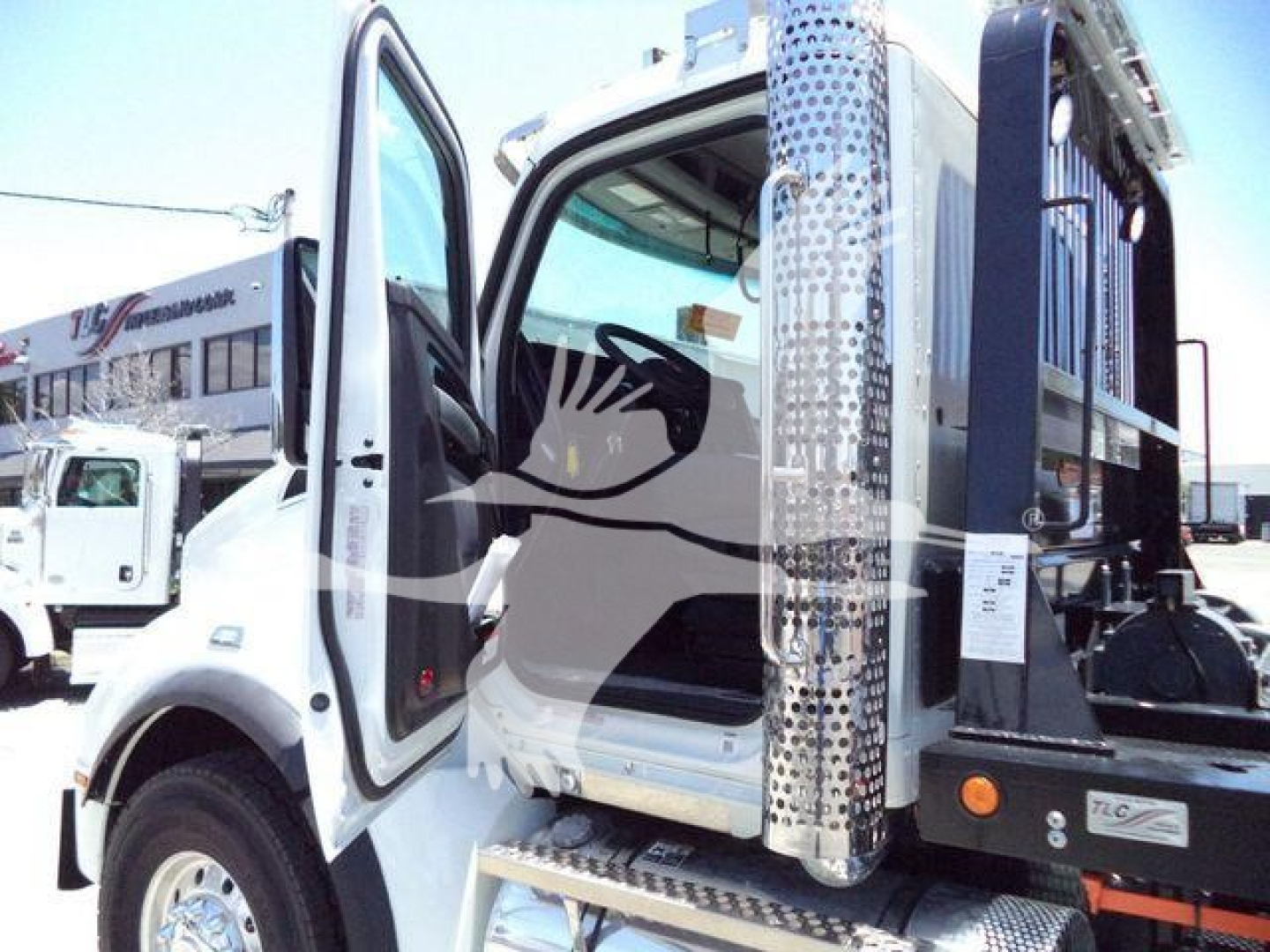 Kenworth T880 cab interior visible with open door, step, and chrome fuel tank area in a rollout truck setting.