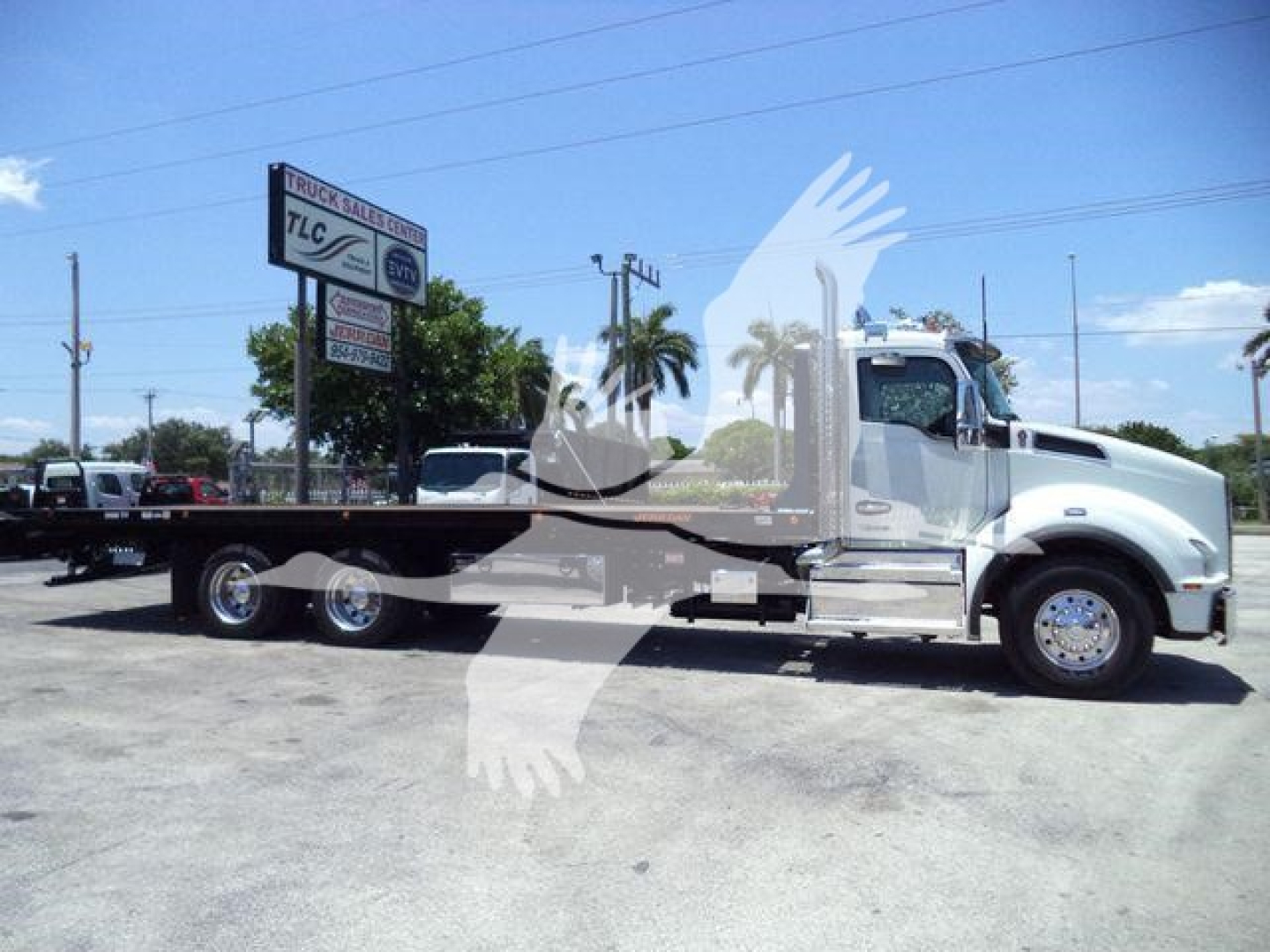 Kenworth T880 rollback truck side view showing long flatbed and chrome cab with wheel assembly.